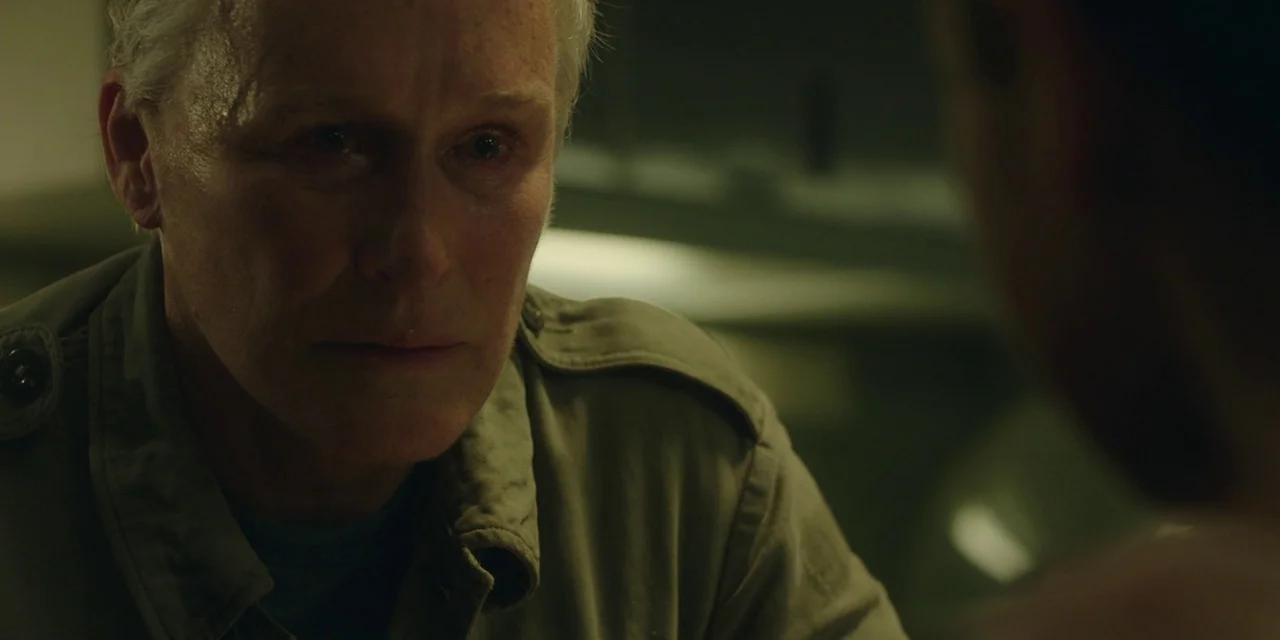 The Girl With All The Gifts (2016) movie still: closeup — An older man is positioned in a dimly lit, nondescript room. He looks directly at someone…