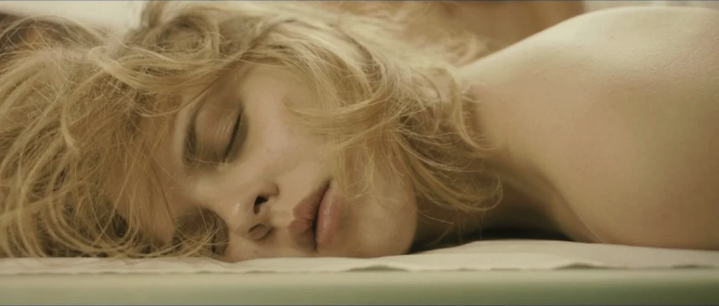 Lasting (Nieulotne) (2013) movie still: closeup — A close-up view of a person lying on a pale treatment table surface. The individual has blonde…
