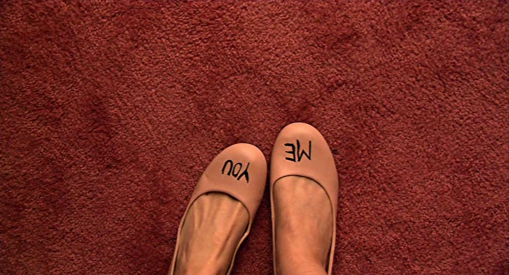 Me and You and Everyone We Know (2005) movie still: closeup — A vibrant red carpet covers the floor beneath a pair of light-colored shoes. The shoes…