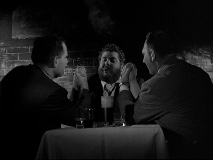 Blast Of Silence (1961) movie still: medium — A dimly lit restaurant interior features a brick wall behind a white-clothed table. Three men sit…