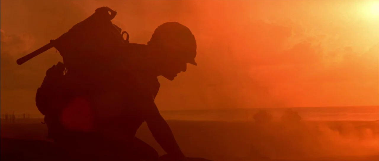Born On The Fourth of July (1989) movie still: medium — A soldier in silhouette kneels on a sandy beach at sunrise. The background shows hazy…