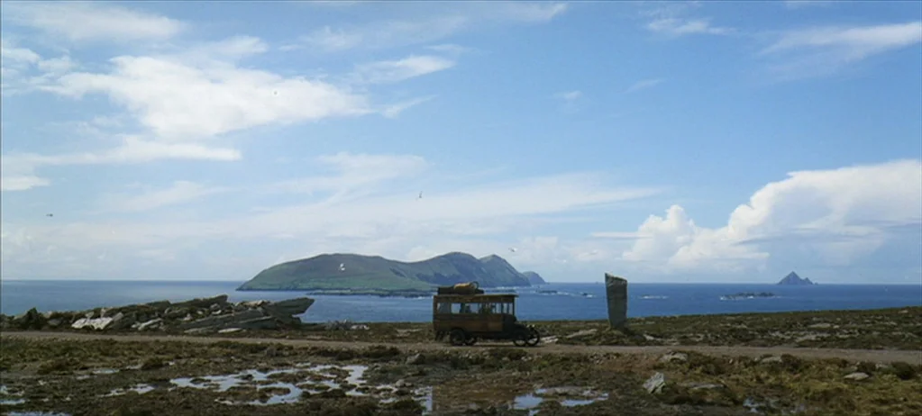 Ryan’s Daughter (1970) movie still: wide — A vintage wooden bus travels along a desolate coastal track overlooking the ocean. Green islands rise…