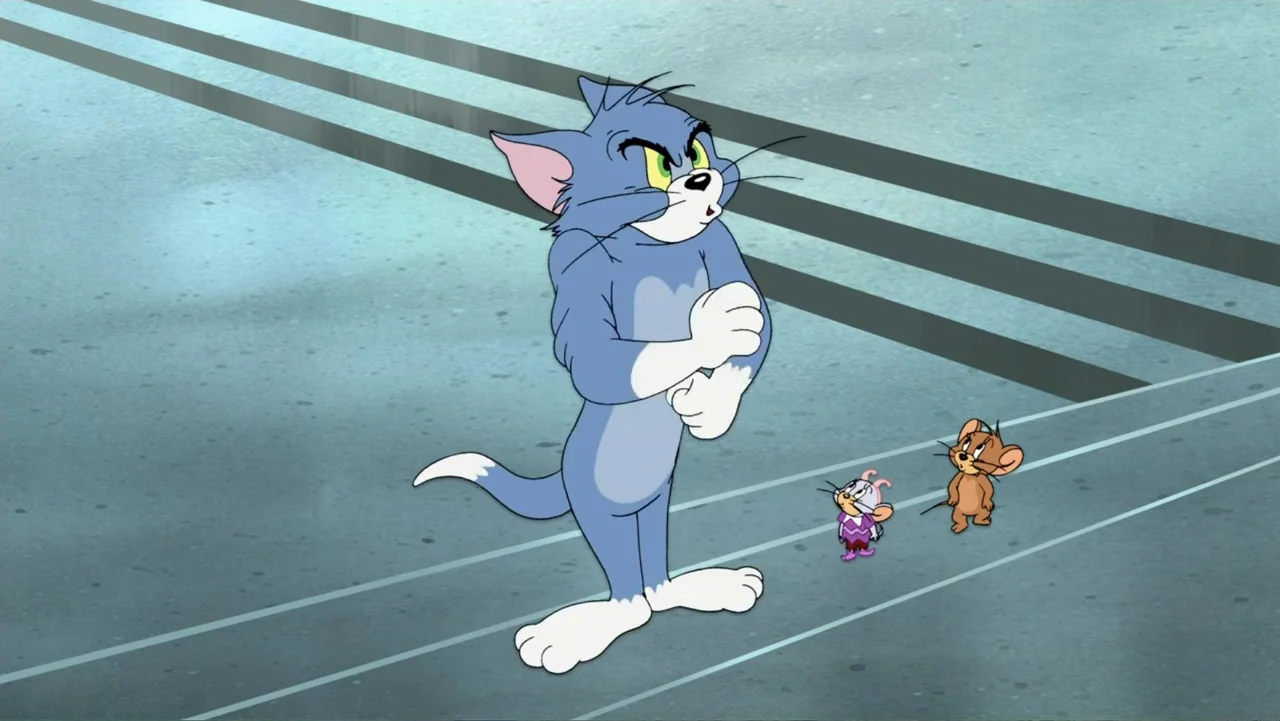 Tom and Jerry & The Wizard of Oz (2011) movie still: fullbody — A blue cat stands on a gray running track with two small mice nearby. The cat faces…