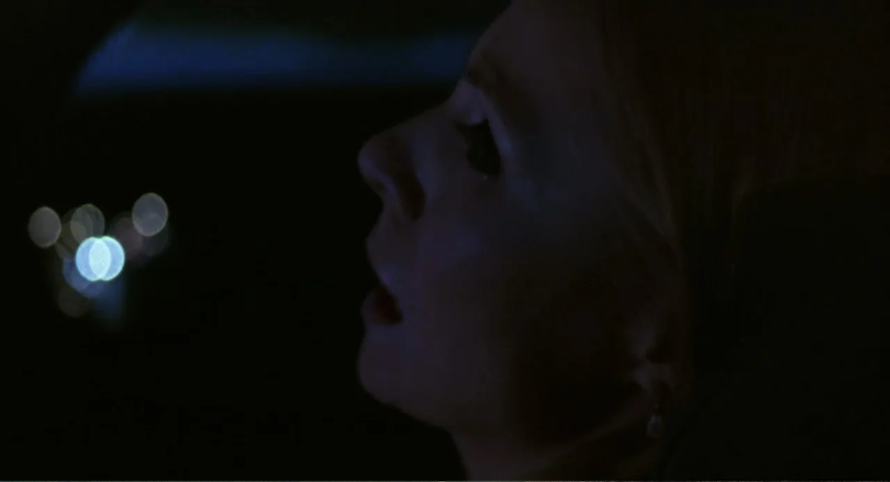 Forty Shades of Blue (2005) movie still: closeup — A dark vehicle interior with blurred out-of-focus city lights visible through the window. A young…