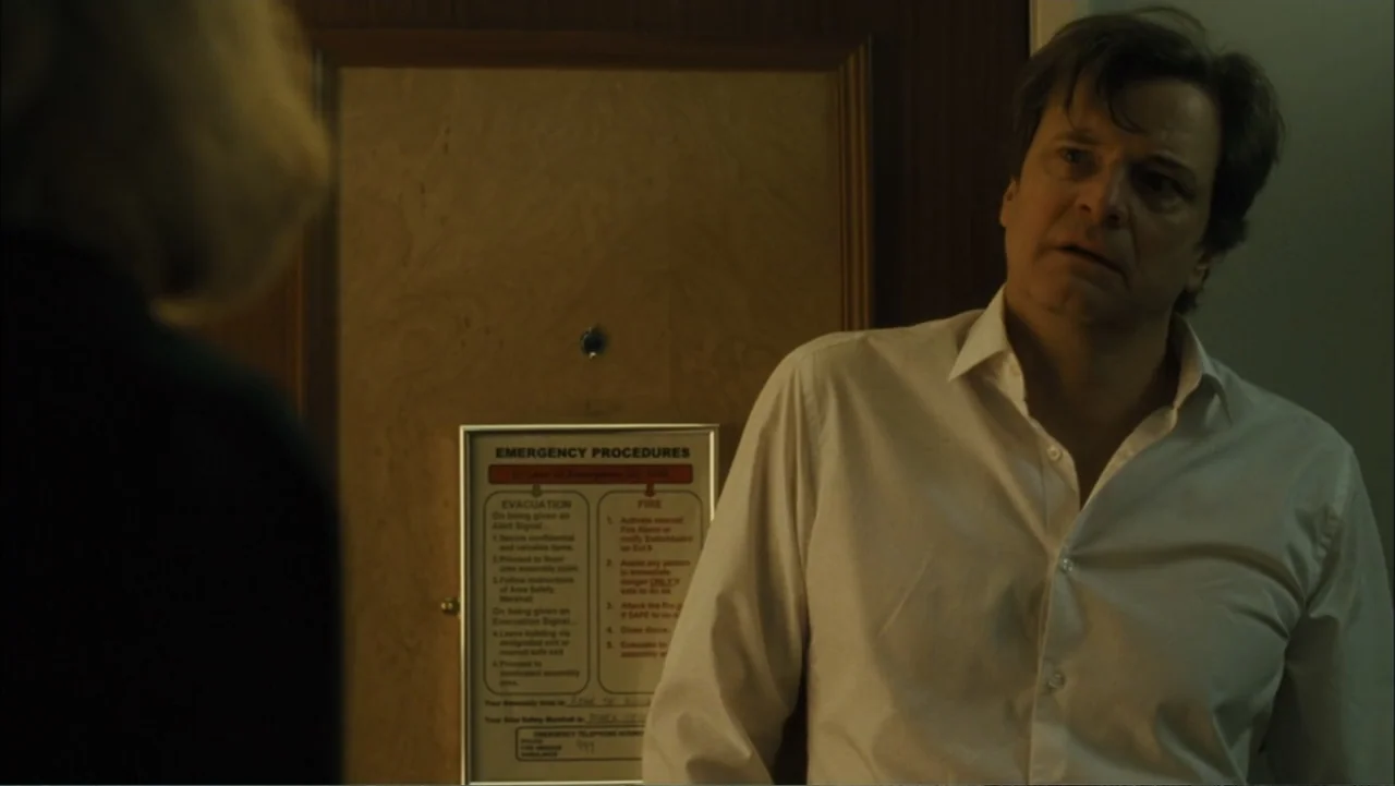 Before I Go to Sleep (2014) movie still: medium — A hotel room door displays an emergency procedures sign mounted on the wood panel. A man in a…