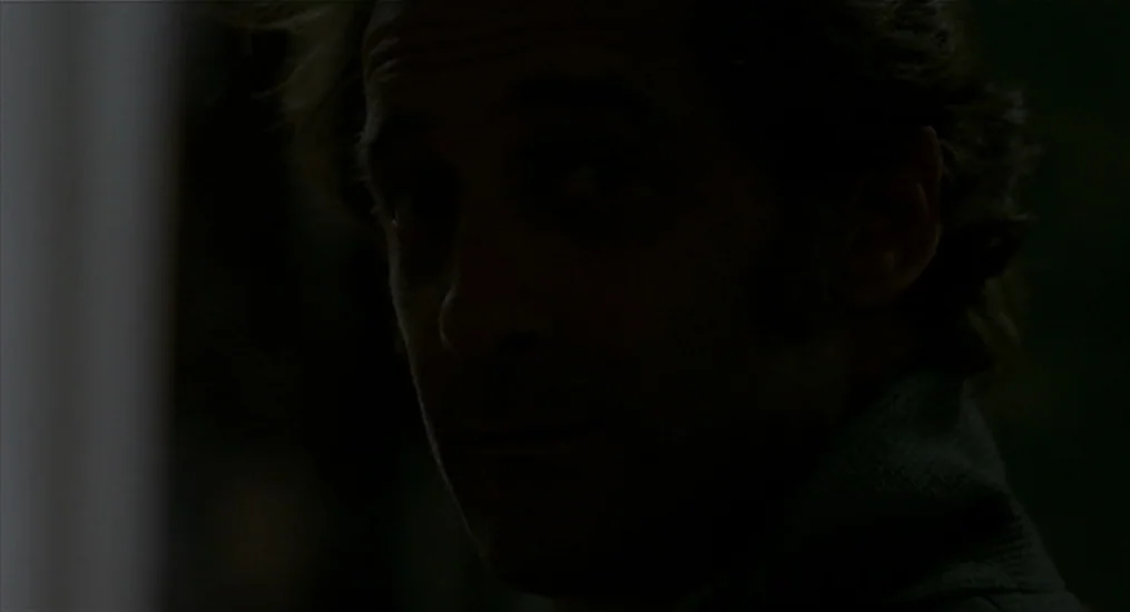 Vendredi Soir (2002) movie still: closeup — A dark, dimly lit interior environment with minimal visible architectural details. A man is positioned…