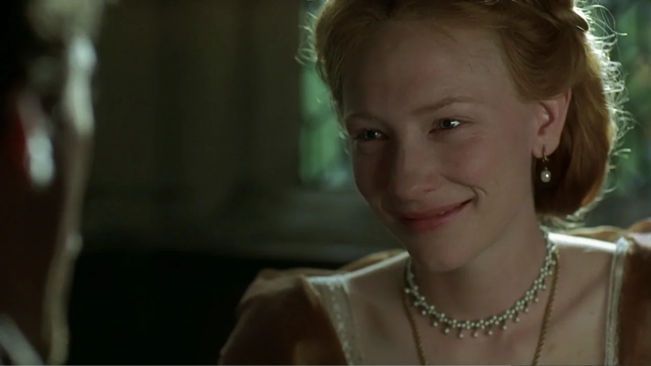 Elizabeth (1998) movie still: closeup — A dimly lit historical interior with wood textures and soft window illumination. A woman with red hair and a…