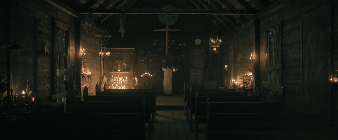 Azrael (2024) movie still: wide — A dark wooden church interior contains rows of empty pews and numerous flickering candles. A lone person stands…