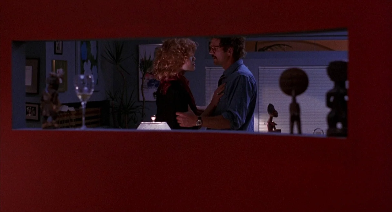 To Live and Die in L.A. (1985) movie still: medium — A man and a woman face each other in a room seen through a rectangular aperture. The foreground…