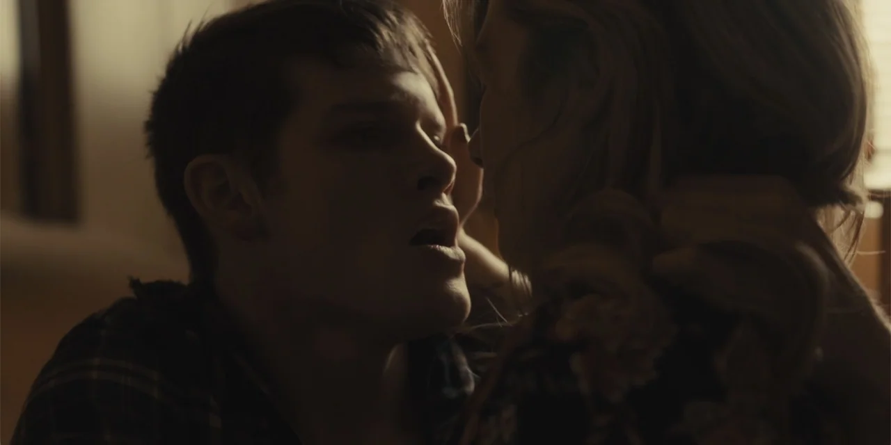 All Roads to Pearla (2019) movie still: closeup — A dimly lit interior room features two individuals in close proximity to one another. The man…