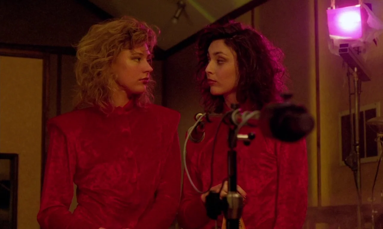 Paganini Horror (1989) movie still: medium — An interior recording space features dark wood paneling and a microphone stand in foreground. Two young…