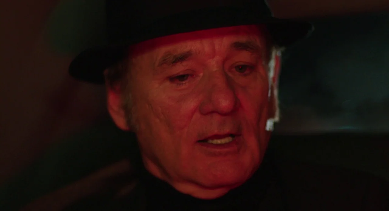 A Glimpse Inside The Mind Of Charles Swan III (2013) movie still: closeup — An older man sits inside a dimly lit vehicle at night. A red light…