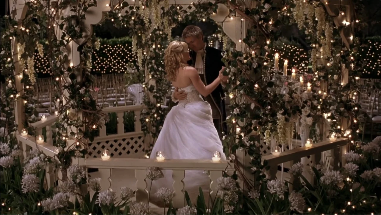 A Cinderella Story (2004) movie still: fullbody — A wooden gazebo is heavily decorated with white flowers, hanging greenery, and numerous small…