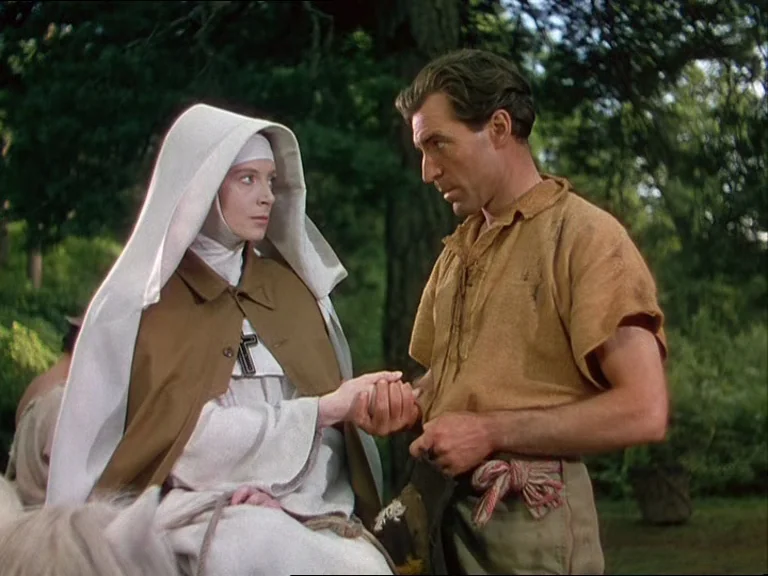 Black Narcissus (1947) movie still: medium — A dense patch of trees serves as the backdrop for two people in conversation. A nun wearing a religious…