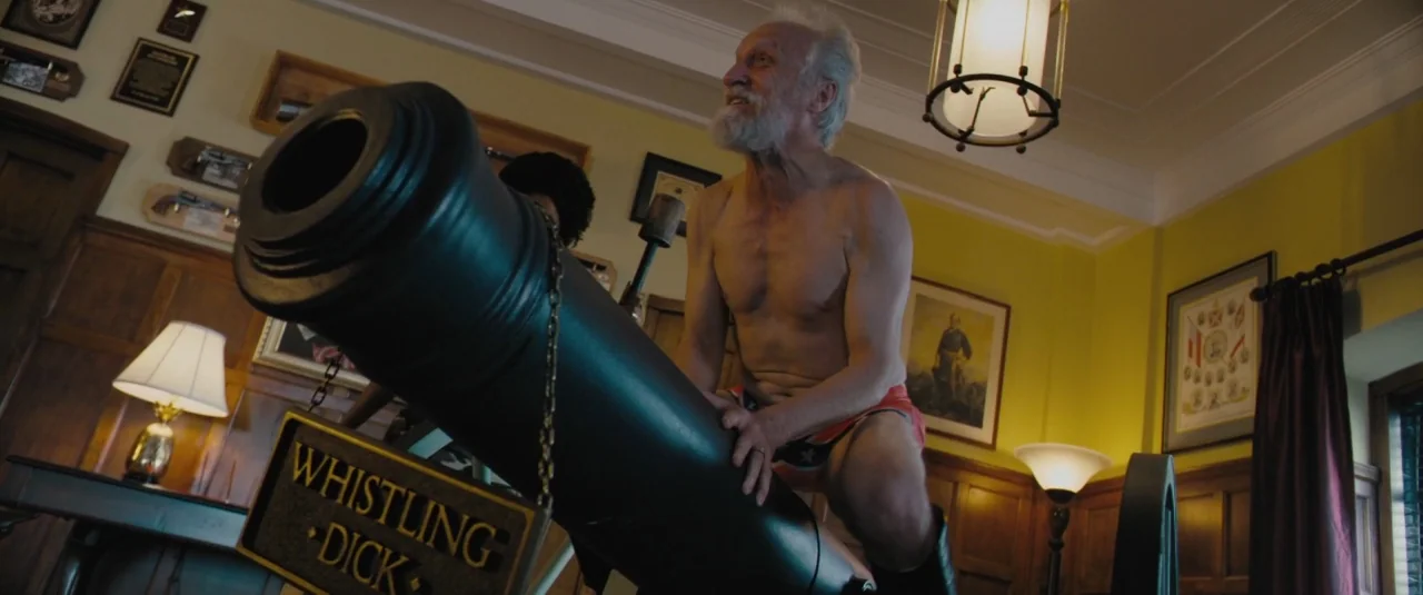 Chi-raq (2015) movie still: medium — A wood-paneled room decorated with framed military certificates and various historic firearms displays. An…