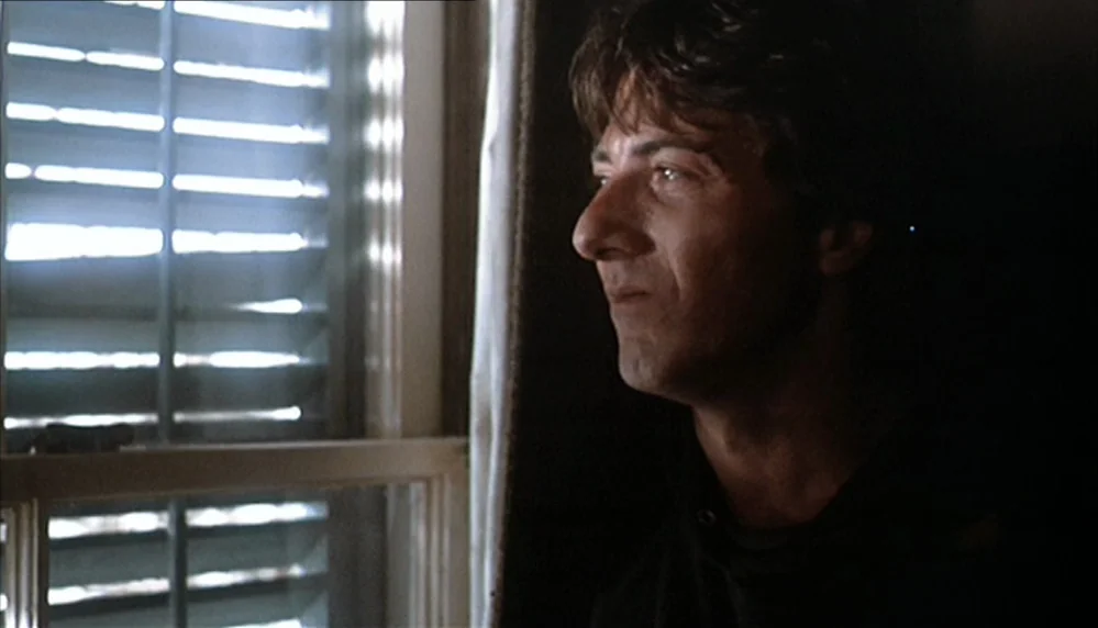 Marathon Man (1976) movie still: closeup — A dimly lit interior space features a window with white horizontal blinds partially closed. A man stands…