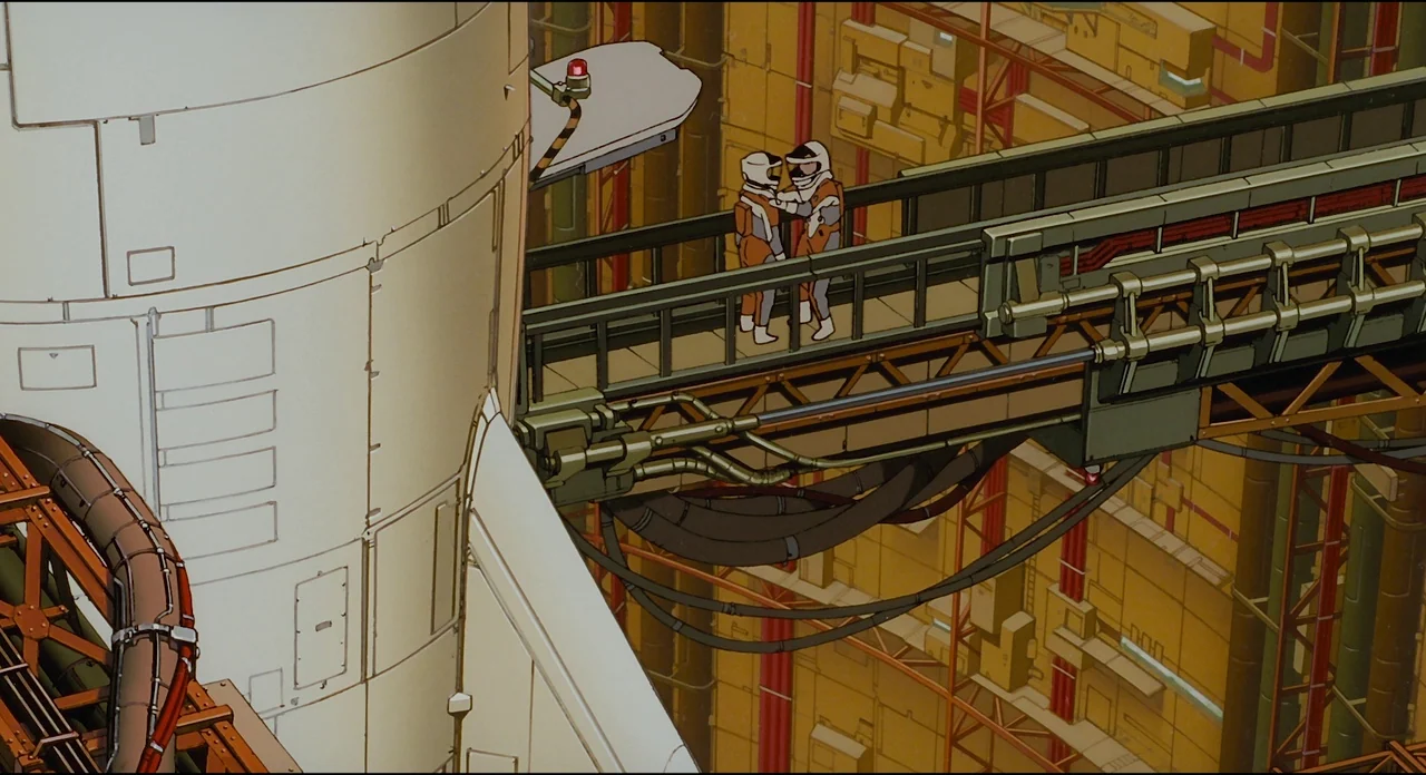 Millenium Actress (2001) movie still: wide — A complex industrial structure features a large rocket shell adjacent to a metal gantry. Two astronauts…