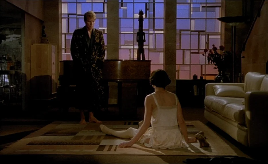 Mélo (1986) movie still: fullbody — An apartment interior features a large glass grid window and a grand piano. A man stands near the piano while a…