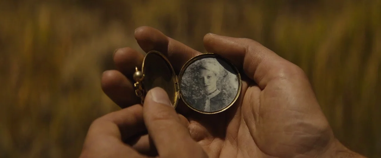 Damsel (2018) movie still: closeup — An open antique metal locket is held in a person's hands. The locket contains a small black-and-white portrait…