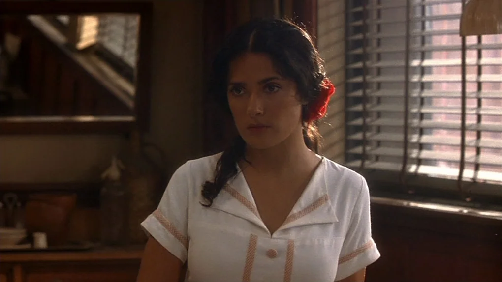 Ask The Dust (2006) movie still: medium — A diner interior with wood paneling and window blinds filtered with daylight. A woman in a white blouse…