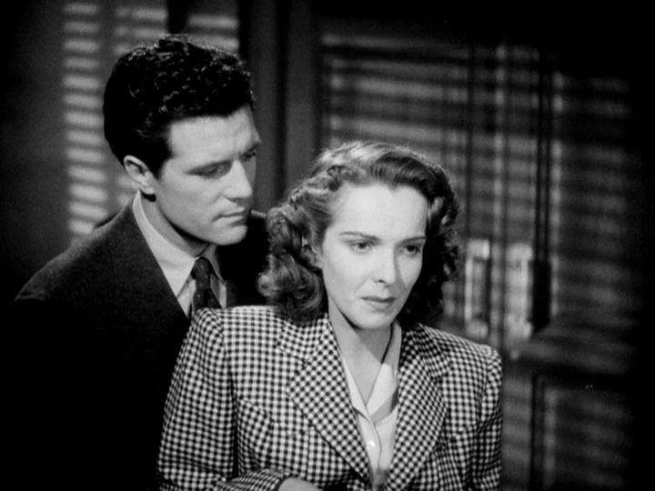 Stranger on the Third Floor (1940) movie still: medium — A man and woman stand close together in front of window blinds. The man stands slightly…