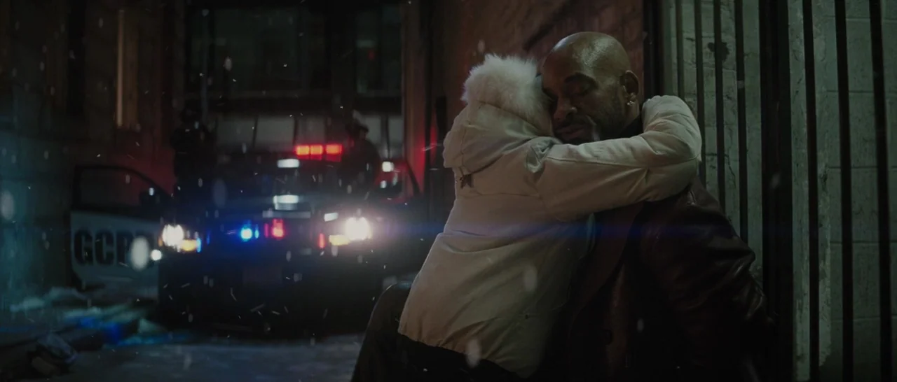 Suicide Squad (2016) movie still: medium — A snow-covered urban street at night with a parked police cruiser in the background. A man in a leather…