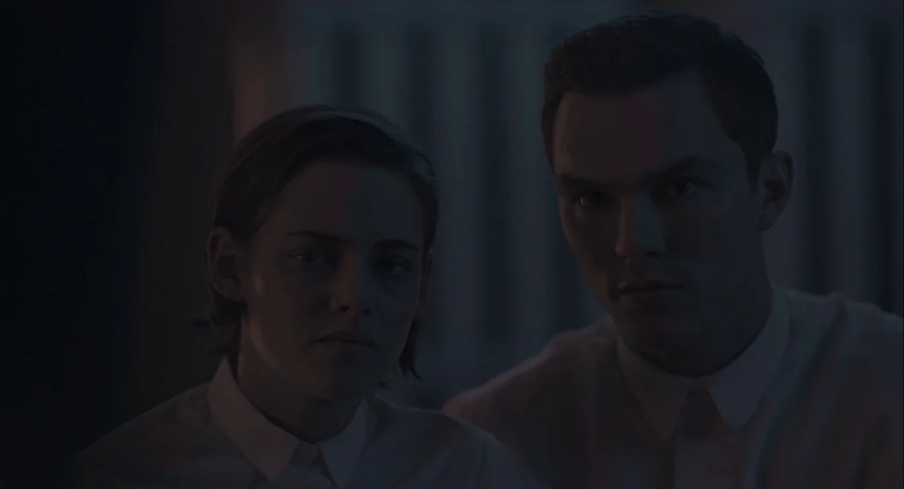 Equals (2015) movie still: medium — A dimly lit interior space features two individuals facing the lens directly. Both subjects wear identical white…