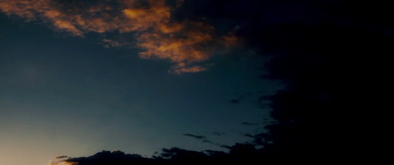 Carriers (2009) movie still: establishing — The sky transitions from a lighter horizon to a dark, cloud-filled expanse. Scattered clouds are…