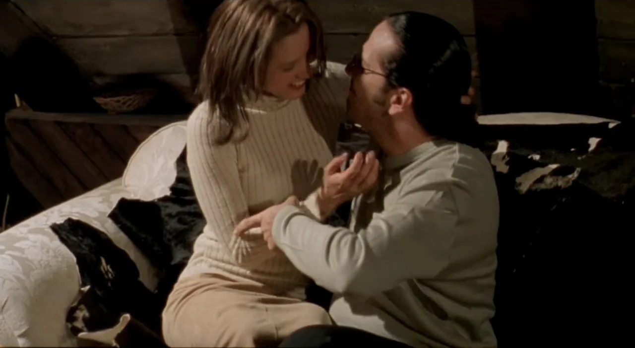 Sex, Love And Other Perversions II (2006) movie still: medium — A room with wooden walls and a sofa covered in a patterned fabric. A couple sits…