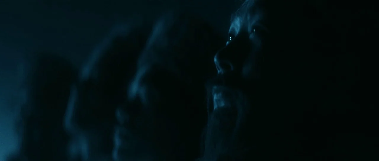 The Bride With White Hair (1993) movie still: closeup — A dimly lit environment with dark silhouettes of people visible in the foreground. A bearded…
