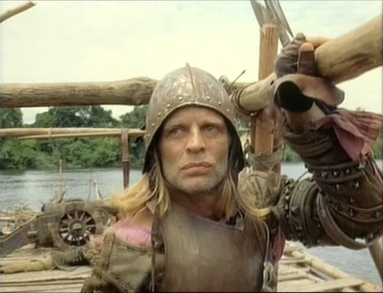Aguirre, The Wrath Of God (Aguirre, der Zorn Gottes) (1972) movie still: medium — A wooden raft floats on a wide river surrounded by dense green…