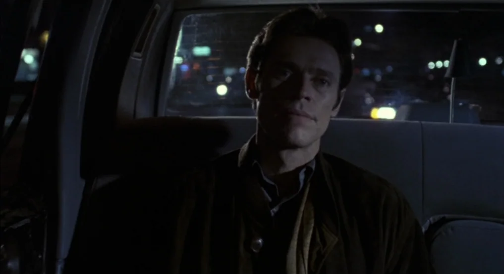 Light Sleeper (1992) movie still: medium — The interior of a moving car at night with city lights visible through the window. A man sits in the back…