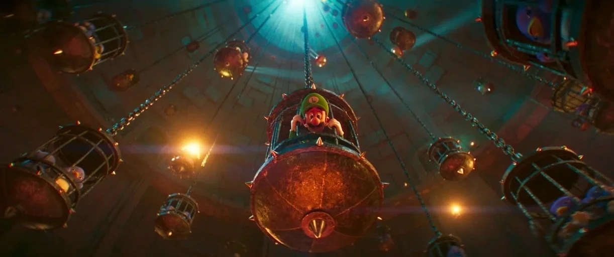 The Super Mario Bros. Movie (2023) movie still: wide — A dark vertical chamber contains multiple hanging metal cages suspended by long heavy chains.…