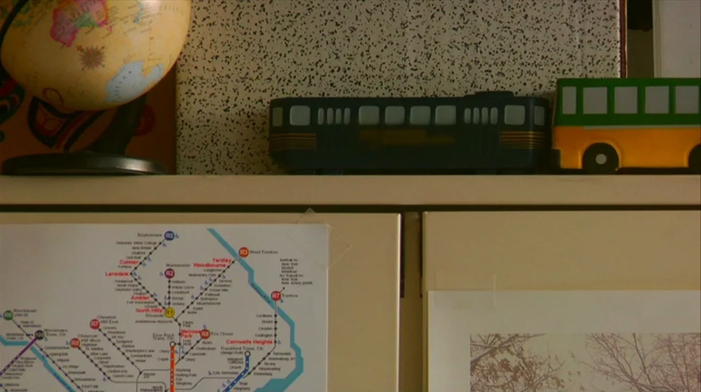 Humpday (2009) movie still: closeup — A cream-colored storage unit holds various decorative objects and a transit map. A vintage globe sits next to…