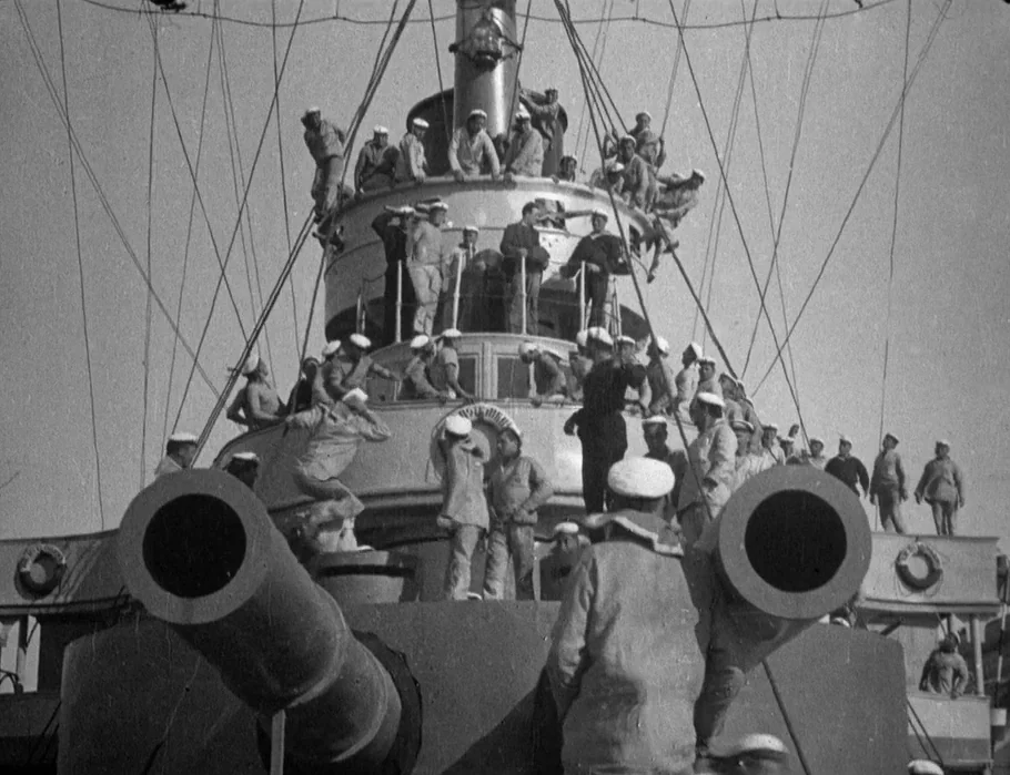 Battleship Potemkin (1925) movie still: wide — A metal battleship deck crowded with numerous sailors near large artillery gun barrels. Many men…