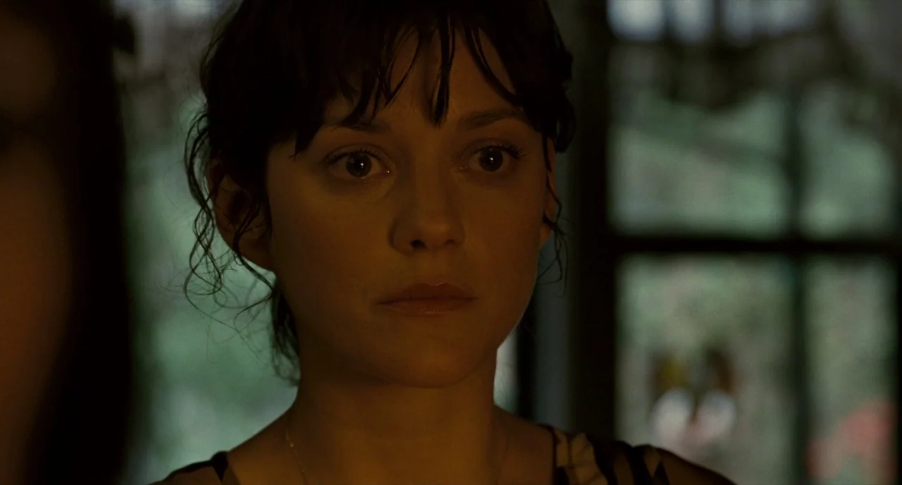 It’s Only The End Of The World (2016) movie still: closeup — A dimly lit indoor space features a window with a blurred green outdoor view. A woman…