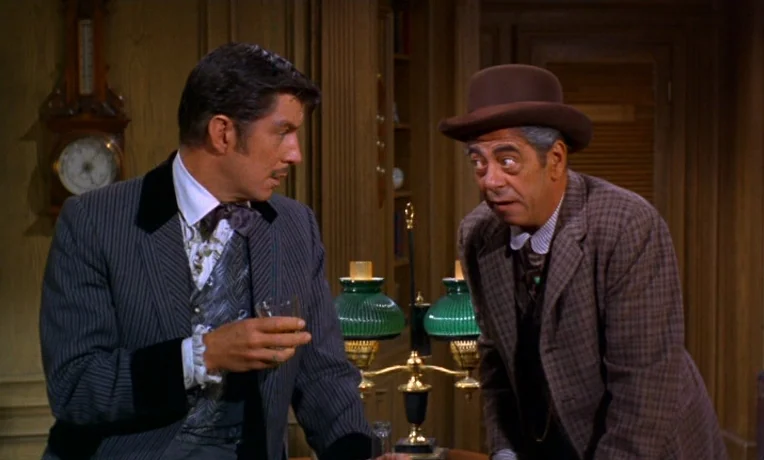 Frankie and Johnny (1966) movie still: medium — A wood-paneled room contains an antique barometer on the wall and a desk lamp. Two men in early…