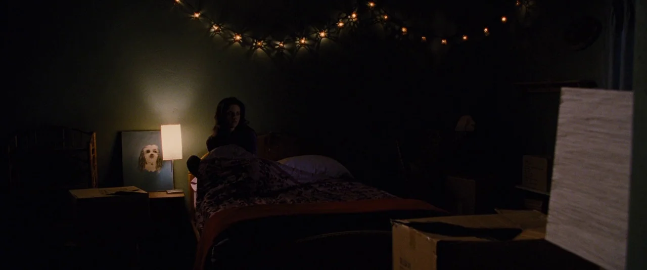 The Twilight Saga: Breaking Dawn – Part 1 (2011) movie still: wide — A dark, sparsely furnished room contains a bed and scattered cardboard storage…