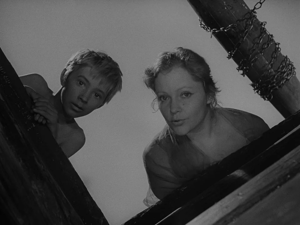 Ivan’s Childhood (1962) movie still: medium — A woman and a young boy look down from the rim of a structure. They are framed by the dark, circular…
