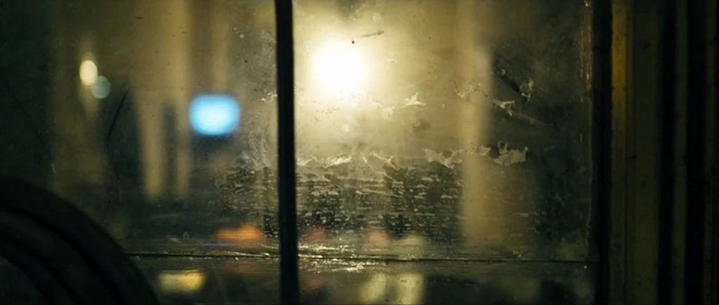 Once Upon a Time in Anatolia (2011) movie still: establishing — A dark, grime-streaked window pane separates the viewer from a blurred nighttime…