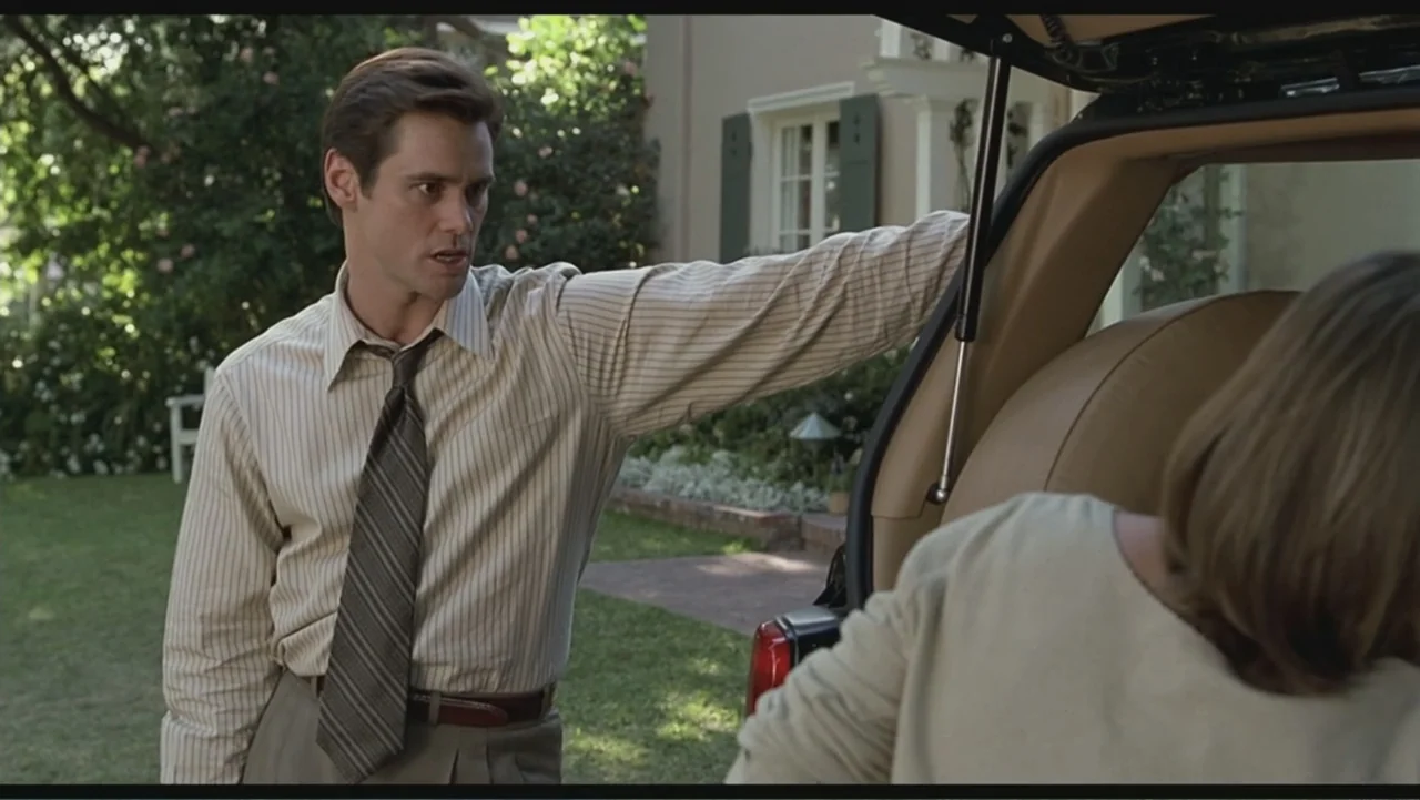 Liar Liar (1997) movie still: medium — A residential driveway with a suburban house visible in the background greenery. A man in a shirt and tie…