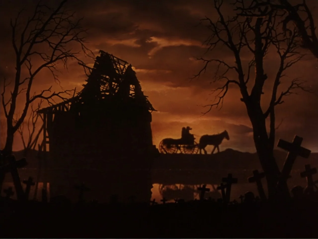 Gone with the Wind (1939) movie still: wide — A silhouette of a dilapidated cabin and grave markers sits against a dark sky. A carriage pulled by a…