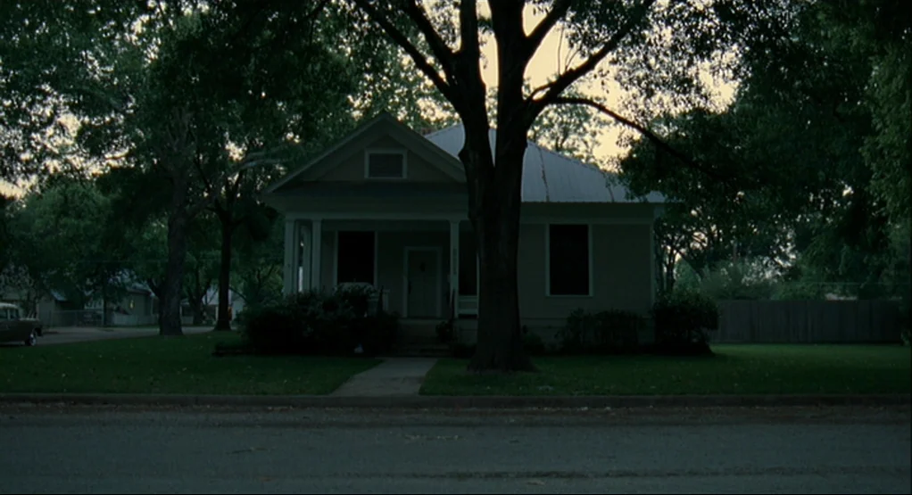 The Tree Of Life (2011) movie still: wide — A single-story suburban house sits behind a large tree in the yard. The street is in the foreground with…
