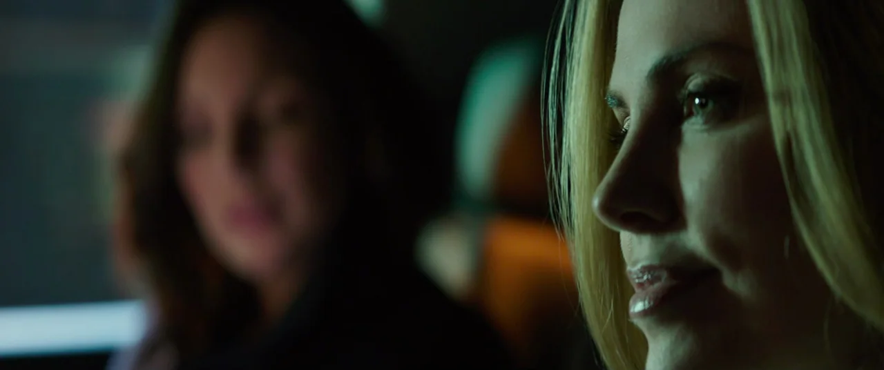 Long Shot (2019) movie still: closeup — The interior of a car at night with soft light illuminating a woman's profile. A second person is visible…