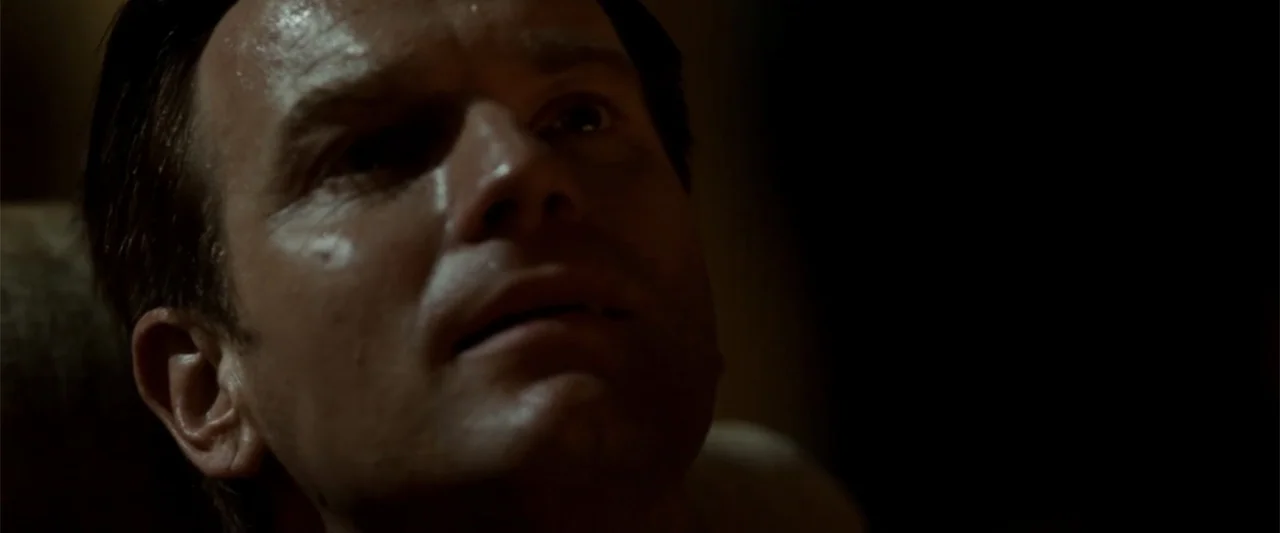 Angels & Demons (2009) movie still: closeup — A dark indoor space where shadows obscure most of the background detail. A man's face is partially lit…