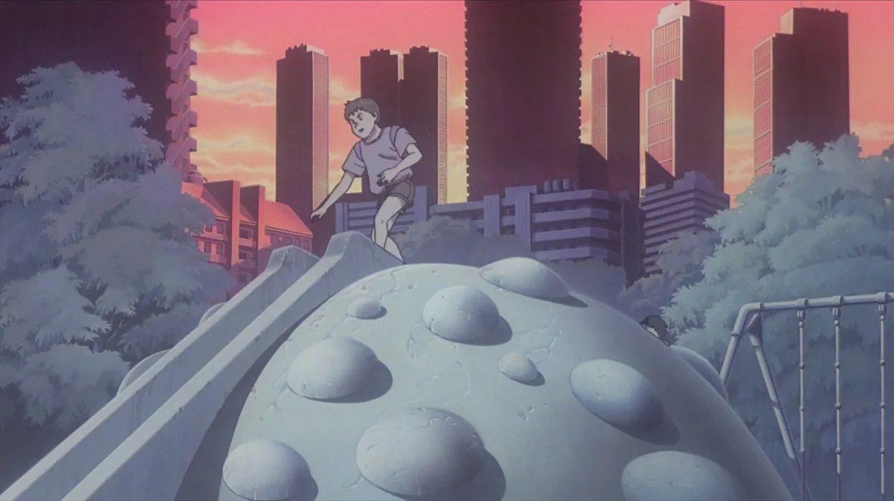 Akira (1988) movie still: medium — A public urban playground at dusk with modern apartment blocks silhouetted against a pink sky. A young boy…