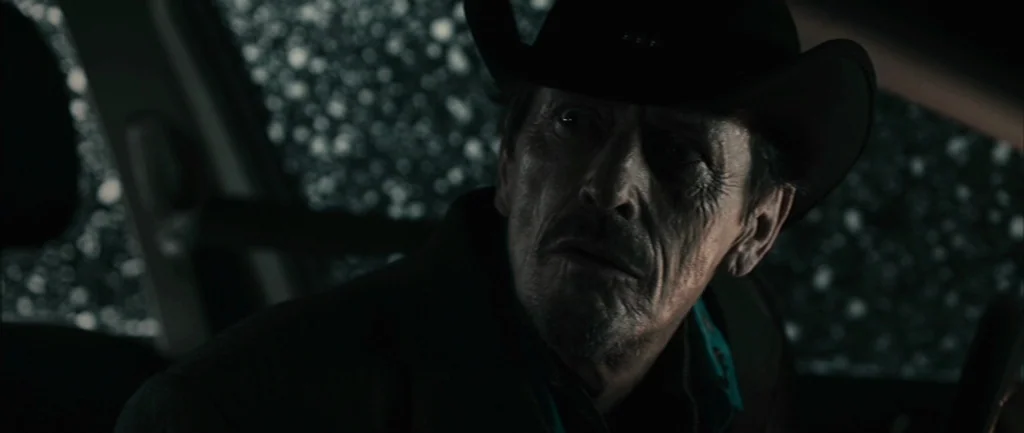 Pontypool (2008) movie still: closeup — An interior of a vehicle during a rainstorm at night with visible raindrops on glass. A man wearing a black…