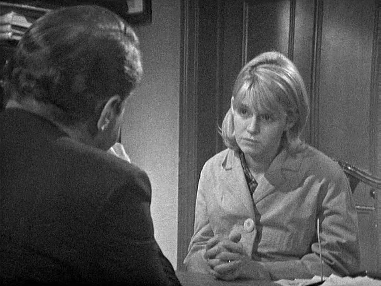 Cathy Come Home (1969) movie still: medium — An office interior features wood-paneled walls and desk furniture in a 1960s style. A blonde woman in a…