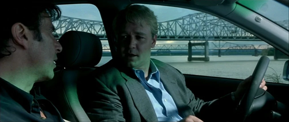 The Insider (1999) movie still: medium — A car interior shows two men talking while parked near a large steel bridge. The background through the…