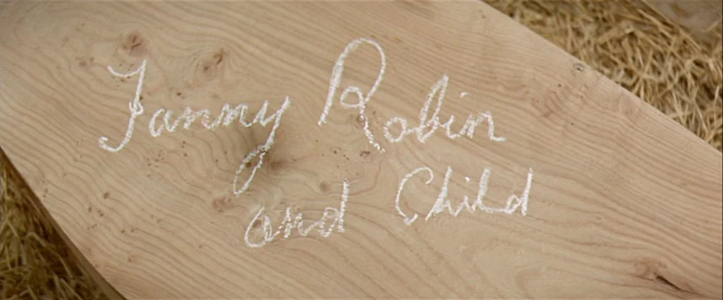 Far from the Madding Crowd (1967) movie still: closeup — A wooden plank lies atop a pile of golden straw in a barn. The words Fanny Robin and Child…